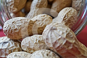 Heap of unpeeled goober nuts (monkey nuts or also called groundnuts) in the glass container