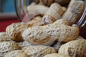 Heap of unpeeled goober nuts (monkey nuts or also called groundnuts) in the glass container