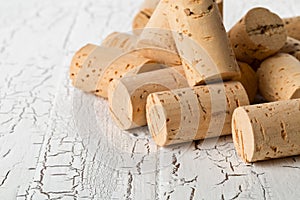 Heap of unused, new, brown natural wine corks on white wooden bo