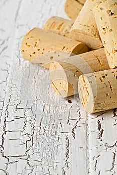 Heap of unused, new, brown natural wine corks on white wooden bo