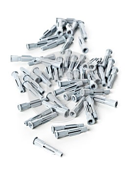 Heap of unused, new, grey plastic wall plug bolts over white