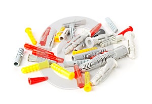 Heap of unused, new, plastic wall plug bolts of multiple sizes, types and colors over white