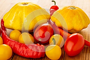 Heap of vegetables, pattison, chili peppers, red and yellow tomatoes on table