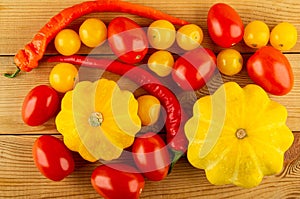 Heap of vegetables, pattison, chili peppers, red and yellow tomatoes on table. Top view