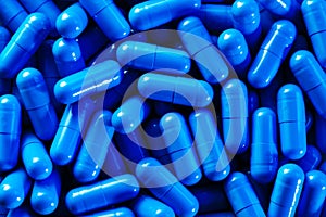 Heap of vivid blue capsule pills close up background