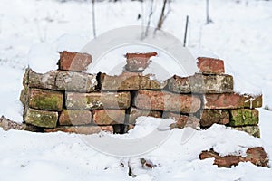 Heap of weathered red brick in the snow