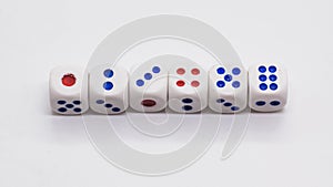 Heap of white cubic tree six dices with blue and red spikes dots on a white background.