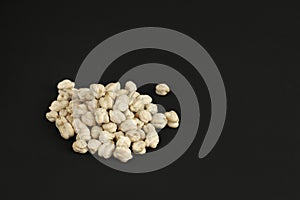 Heap of white dried chickpeas on black background with copy space