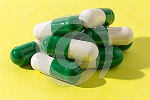 Heap of white and green capsules on white background. Pile of pi