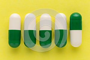 Heap of white and green capsules on white background. Pills are