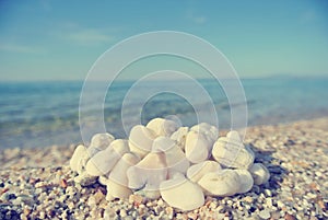 Heap of white pebbles on pebbly beach; faded, retro style
