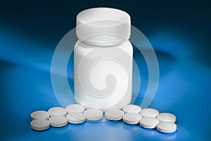 Heap of white pills and a white pill bottle on blue background