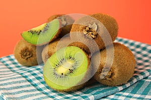 Heap of whole and cut fresh kiwis on orange background, closeup