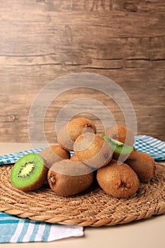 Heap of whole and cut fresh kiwis on white table, space for text