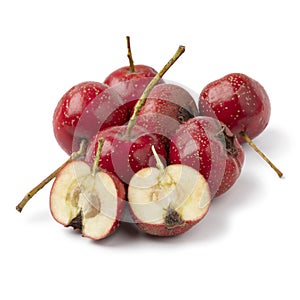 Heap of whole and halved ripe fresh red hawthorne berry close up on white background