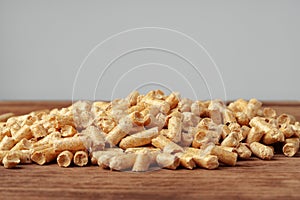 Heap of wooden pellets biofuel on wooden table close up