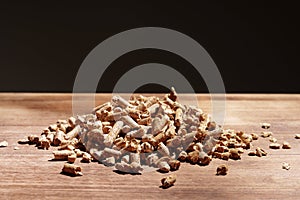 Heap of wooden pellets biofuel on wooden table close up