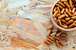 Heap of yellow pills in the wooden bowl or yellow capsule on the wood background.