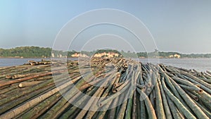 Heaps of bamboo poles tied together and pulled behind a small boat down the river