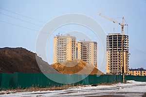 Heaps of chernozem and sand behind fence on building site
