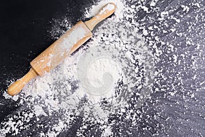 Heaps of wheat flour with ears of wheat on the table, black background - top view