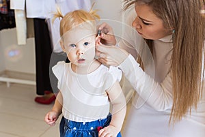 Hearing aid in baby girl`s ear. Toddler child wearing a hearing aid at home. Disabled child, disability and deafness