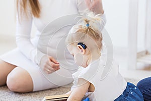 Hearing aid in baby girl`s ear. Toddler child wearing a hearing aid at home. Disabled child, disability and deafness