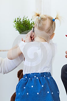 Hearing aid in baby girl`s ear. Toddler child wearing a hearing aid at home. Disabled child, disability and deafness