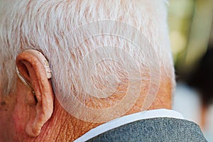 a hearing aid behind the ear of an elderly man.
