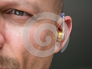 Hearing aid in the ear of a man with suffering from deafness and hearing impairment