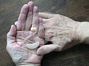 Hearing aid in human hands. Electronic medical device that is wore behind the ear