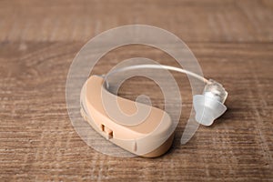 Hearing aid on wooden table, closeup.