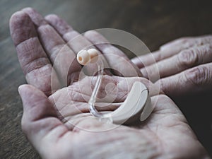 Hearing device in hand of elder person. World hearing day