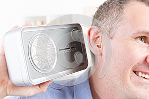 Hearing impaired man trying to listen radio photo