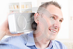 Hearing impaired man trying to listen radio photo