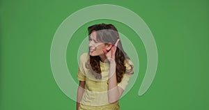 Hearing problem. Young girl put hands near ears, try to listen quiet talk gossip, find out information on green backdrop