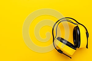 Hearing protection industrial ear muffs on yellow background. top view of yellow protective ear muffs with copy space