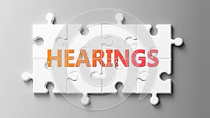 Hearings complex like a puzzle - pictured as word Hearings on a puzzle pieces to show that Hearings can be difficult and needs photo