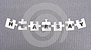 HEARSAY - word composed of paper white puzzles on a gray background photo