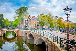 Heart of Amsterdam in one photo - leaning houses, bridges, canals, bicycles and lanterns. View of the famous old center of