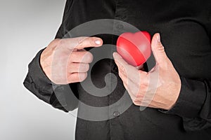 Heart attack, illness or falling in love concept. Man with a red rubber heart