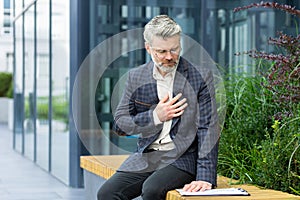 Heart attack in mature businessman on air, senior boss has severe chest pain, gray-haired man has heartache sitting on