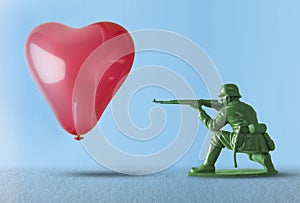 Heart balloon as a target for a soldier shooting a gun - concept for love and war