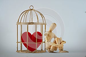 Heart in a bird cage and wooden mannequin - Love and closed heart concept