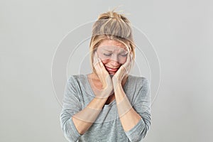 Heart broken young blond woman crying expressing feelings under shock