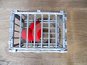 Heart in the cage Put on a wooden table, It shows the closure of freedom and love. Love is disappointed and not satisfied. Closing