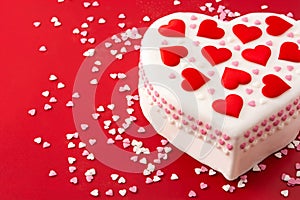 Heart cake for St. Valentine`s Day, Mother`s Day, or Birthday, decorated with sugar hearts on red background.