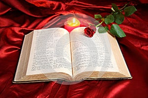 Heart candle on open Bible and red rose