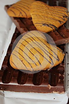 Heart chaped cookies and brown chocolate on white background close-up.