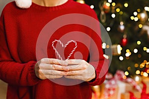 A heart of Christmas candy in the hands of a girl in a red sweater.